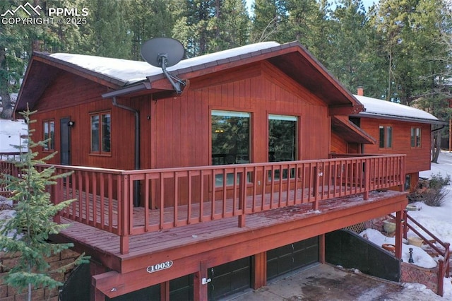 snow covered back of property with a deck