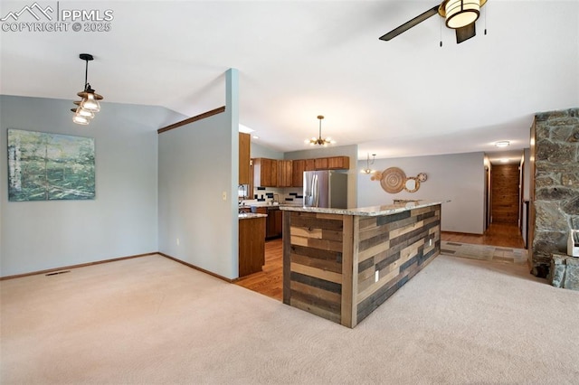 kitchen with pendant lighting, light colored carpet, and stainless steel fridge