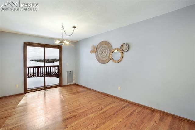 empty room featuring a notable chandelier and light hardwood / wood-style floors