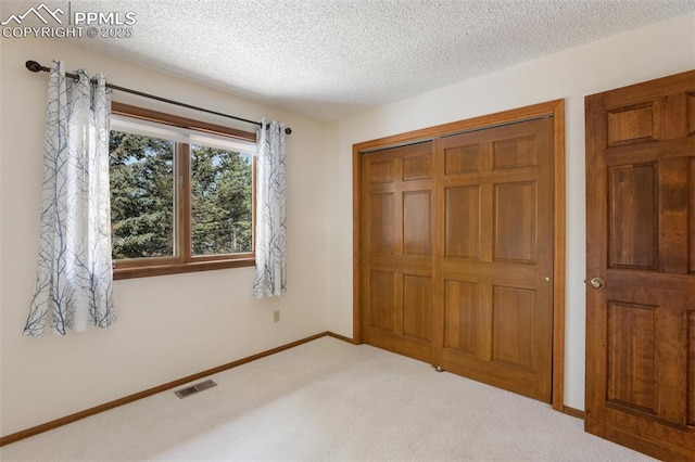 unfurnished bedroom featuring carpet, a textured ceiling, and a closet