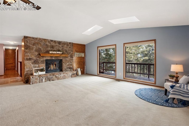 carpeted living room with lofted ceiling with skylight and a fireplace