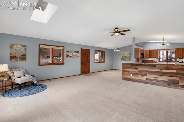 living room featuring light carpet, ceiling fan with notable chandelier, and vaulted ceiling