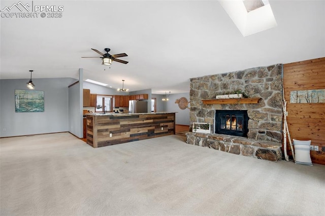 carpeted living room with lofted ceiling, sink, ceiling fan with notable chandelier, a stone fireplace, and wood walls