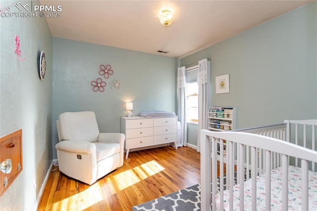 bedroom featuring light hardwood / wood-style flooring and a nursery area