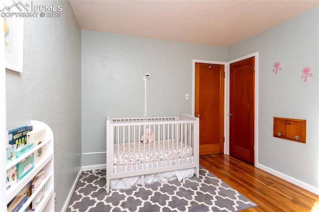 bedroom featuring wood-type flooring and a nursery area