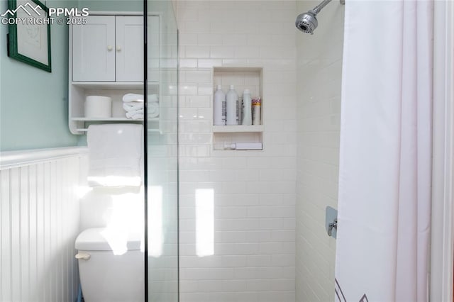 bathroom featuring tiled shower and toilet