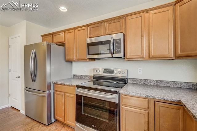 kitchen with appliances with stainless steel finishes and light hardwood / wood-style flooring