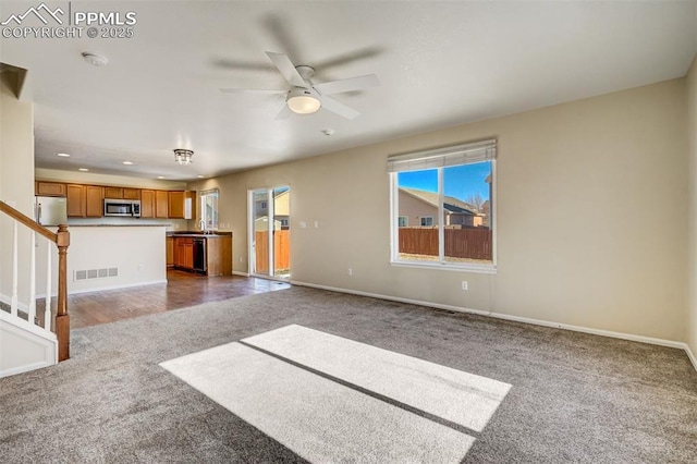 unfurnished living room with ceiling fan and carpet