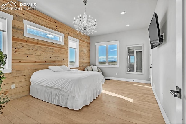 bedroom featuring light wood-type flooring, a chandelier, and wooden walls