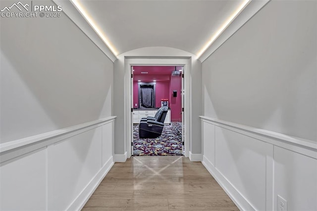 hallway with vaulted ceiling and light hardwood / wood-style flooring