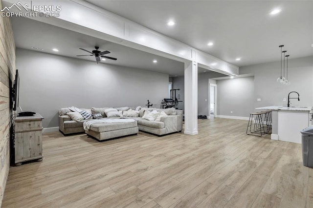 living room with ceiling fan, sink, and light hardwood / wood-style floors