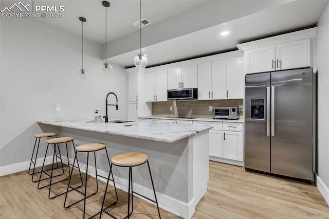 kitchen with appliances with stainless steel finishes, white cabinetry, sink, hanging light fixtures, and kitchen peninsula