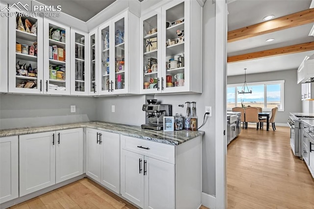 bar with high end range, white cabinetry, light hardwood / wood-style floors, light stone countertops, and beam ceiling