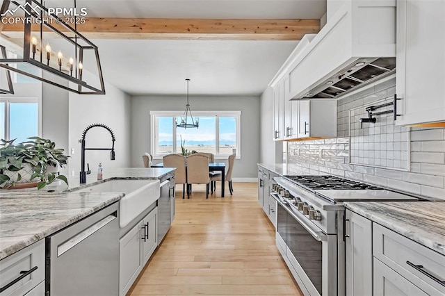 kitchen with stainless steel appliances, custom exhaust hood, white cabinets, and hanging light fixtures