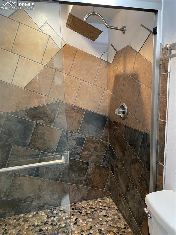 bathroom with toilet and tiled shower