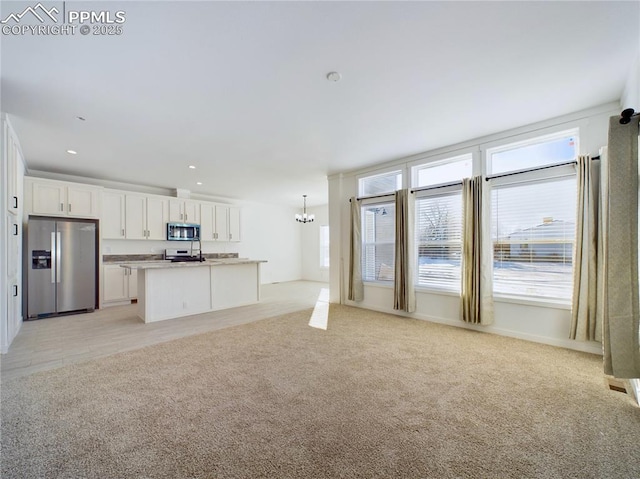 unfurnished living room featuring an inviting chandelier and light colored carpet