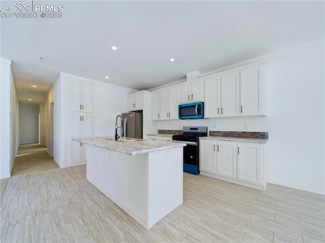 kitchen featuring stainless steel appliances, sink, white cabinetry, and a kitchen island with sink