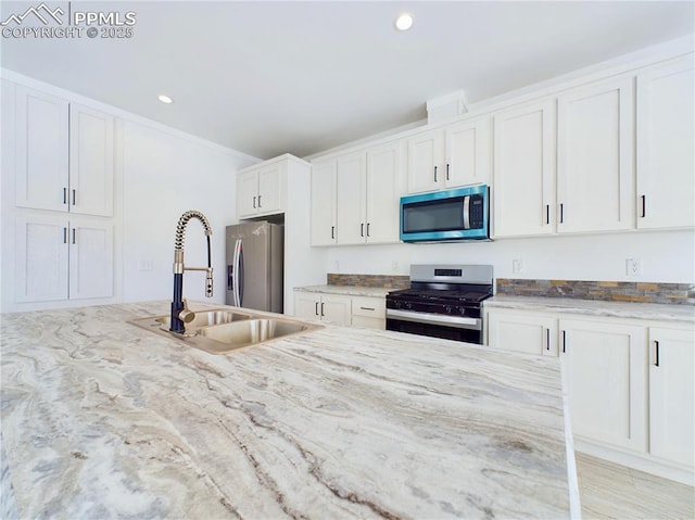 kitchen featuring light stone countertops, sink, stainless steel appliances, and white cabinetry