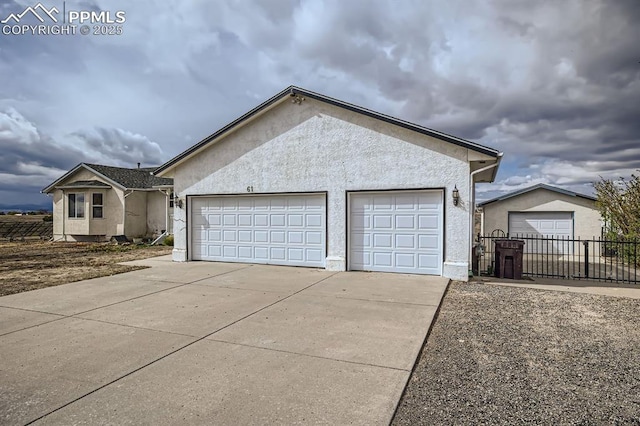 view of front facade with concrete driveway, fence, and stucco siding