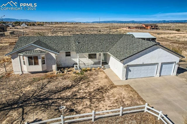 ranch-style home with a mountain view, a garage, fence, concrete driveway, and stucco siding