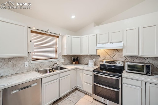 kitchen featuring appliances with stainless steel finishes, white cabinets, lofted ceiling, and sink