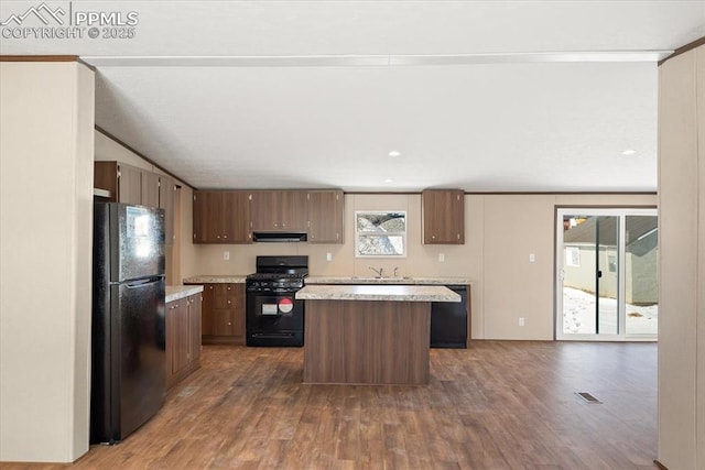 kitchen featuring black appliances, dark hardwood / wood-style flooring, a center island, and a wealth of natural light