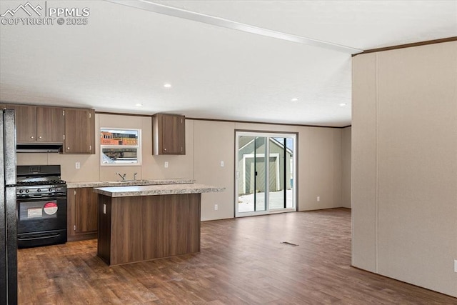 kitchen featuring dark wood-type flooring, black range with gas cooktop, a wealth of natural light, and a center island