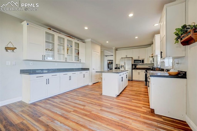 kitchen with sink, white cabinets, a center island, light hardwood / wood-style floors, and appliances with stainless steel finishes