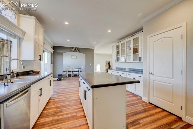 kitchen featuring sink, white cabinets, ornamental molding, stainless steel dishwasher, and a kitchen island