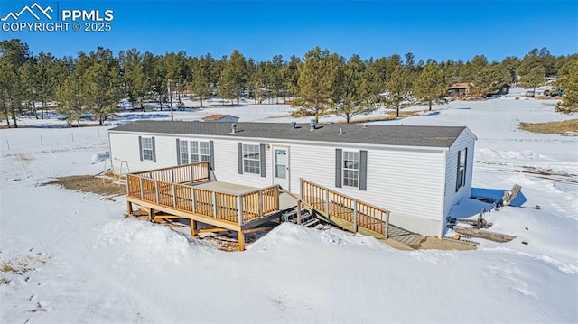 snow covered rear of property with a wooden deck