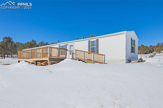 snow covered back of property with a deck