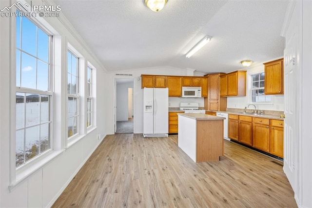 kitchen featuring a kitchen island, light wood-type flooring, lofted ceiling, and white appliances