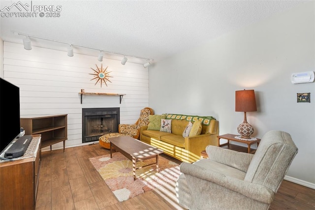 living room featuring a textured ceiling, hardwood / wood-style floors, track lighting, and a fireplace