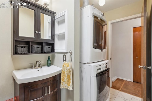 laundry room featuring stacked washer / drying machine, sink, and cabinets