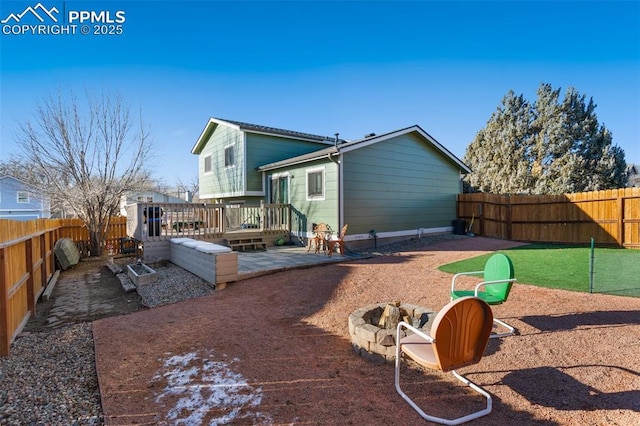 rear view of house featuring a wooden deck and an outdoor fire pit