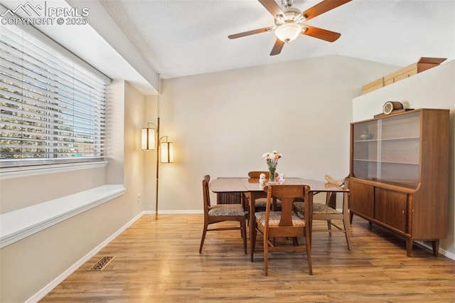 dining area with vaulted ceiling, ceiling fan, and light hardwood / wood-style flooring