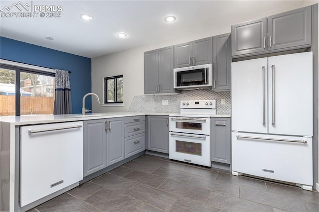 kitchen featuring white appliances, plenty of natural light, sink, kitchen peninsula, and gray cabinetry