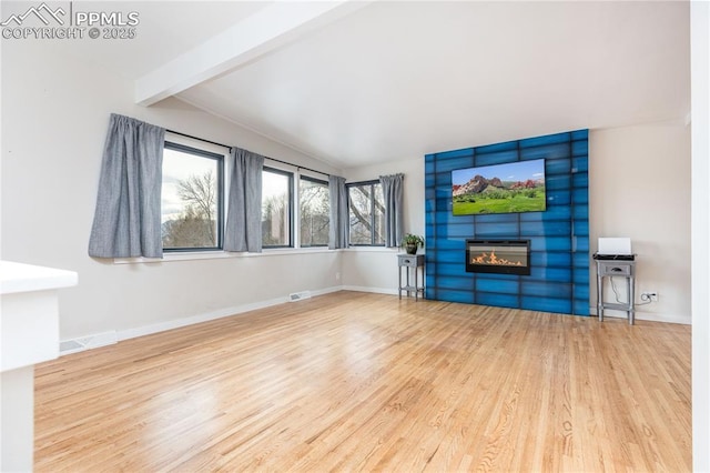 unfurnished living room with a large fireplace, hardwood / wood-style floors, and lofted ceiling with beams