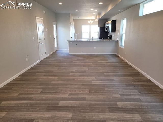 interior space featuring a notable chandelier, dark hardwood / wood-style floors, kitchen peninsula, and fridge