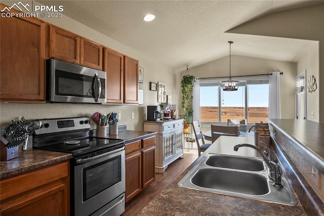 kitchen featuring stainless steel appliances, decorative light fixtures, lofted ceiling, a chandelier, and sink