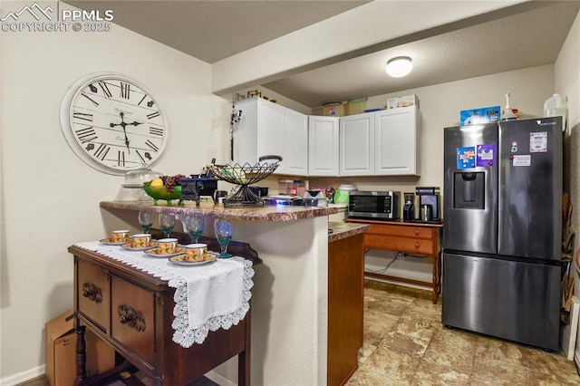 kitchen with a kitchen bar, white cabinets, appliances with stainless steel finishes, and kitchen peninsula