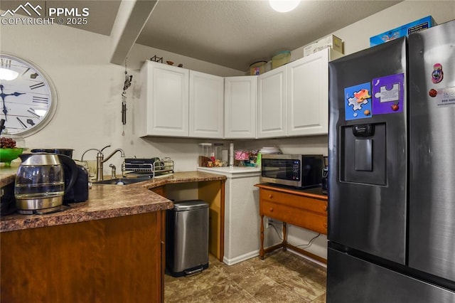 kitchen featuring a textured ceiling, stainless steel appliances, white cabinetry, and sink