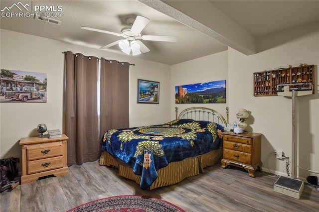 bedroom with ceiling fan, hardwood / wood-style flooring, and beamed ceiling