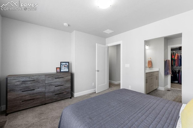 bedroom with a spacious closet, light colored carpet, connected bathroom, and a closet