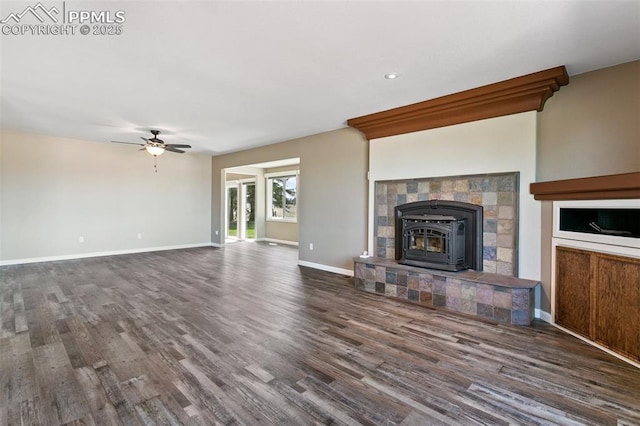 unfurnished living room featuring ceiling fan, a wood stove, and dark hardwood / wood-style flooring