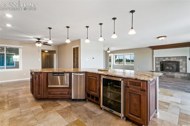 kitchen featuring light stone counters, beverage cooler, pendant lighting, and a center island