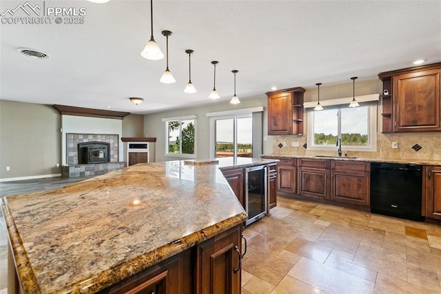 kitchen with dishwasher, a tile fireplace, pendant lighting, sink, and plenty of natural light