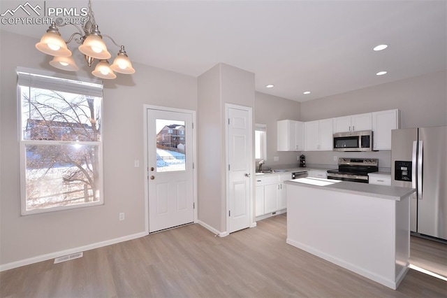 kitchen with white cabinetry, stainless steel appliances, a notable chandelier, decorative light fixtures, and a center island