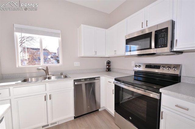 kitchen with sink, white cabinetry, appliances with stainless steel finishes, and light hardwood / wood-style flooring