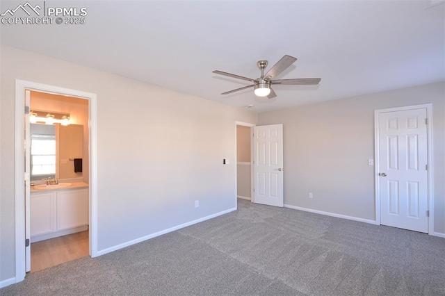 unfurnished bedroom featuring ceiling fan, sink, dark carpet, and ensuite bath